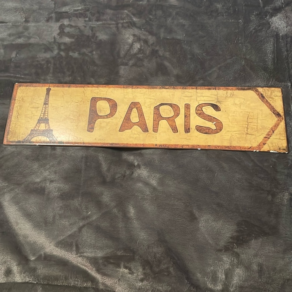 Metal sign that says Paris on it, 1 end has the Eiffel Tower, forward  arrow